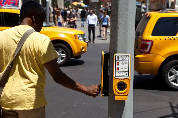 A person pressing the Accessible Pedestrian Signal to cross the street in New York City