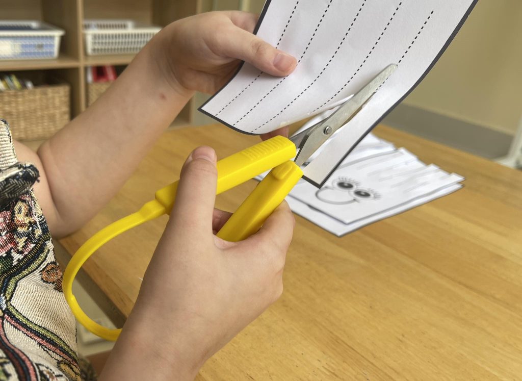 Person using loop scissors to cut a piece of paper to demonstrate its use