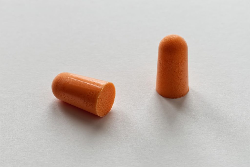 Orange foam earplugs on a white background.